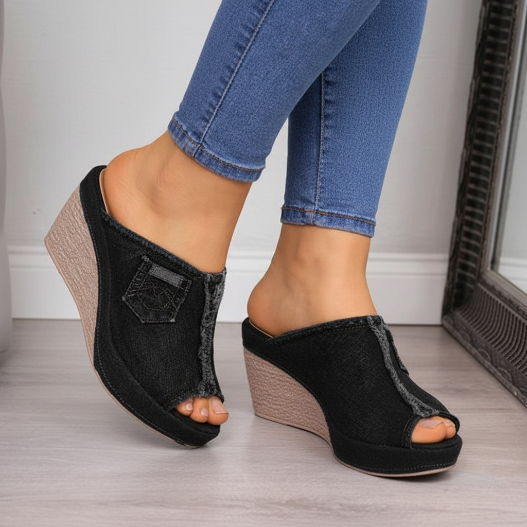 Close-up feet in black denim wedge mule sandals